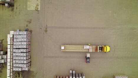 aerial view of yellow semi truck being loaded by forklifts in logistics yard