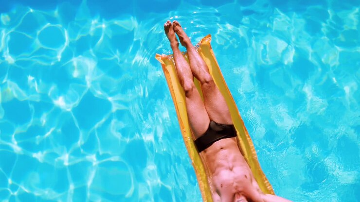 Fit man relaxing on lilo in swimming pool