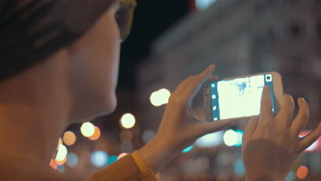 girl with cell phone making photos of evening city