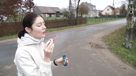 Foto-Lateral-De-Una-Joven-Mujer-Que-Sopla-Burbujas-De-Jabón-Al-Aire-Libre-El-Viento-Sopla-En-La-Calle-En-Otoño