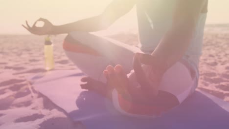 animation of light spots over african american man meditating at beach