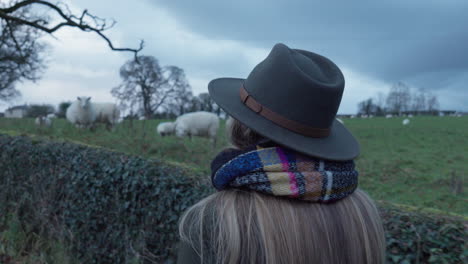 mujer paseando por campo de ovejas