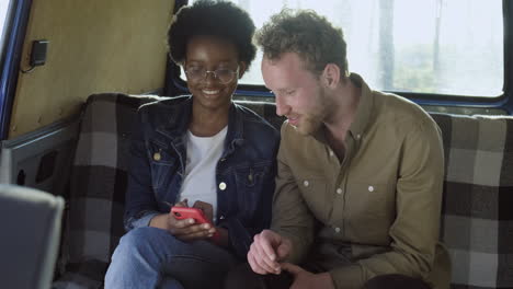 an young woman talks with a guy in a caravan while watching her cellphone