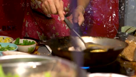 Mujer-Tailandesa-Cocinando-Tortilla-De-Huevo-Sobre-El-Fuego-En-El-Barrio-Chino,-Bangkok,-Tailandia---Cierre-A-Cámara-Lenta