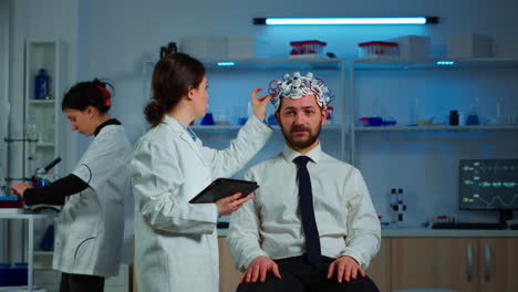 paciente con auriculares de exploración de ondas cerebrales discutiendo con un investigador neurológico
