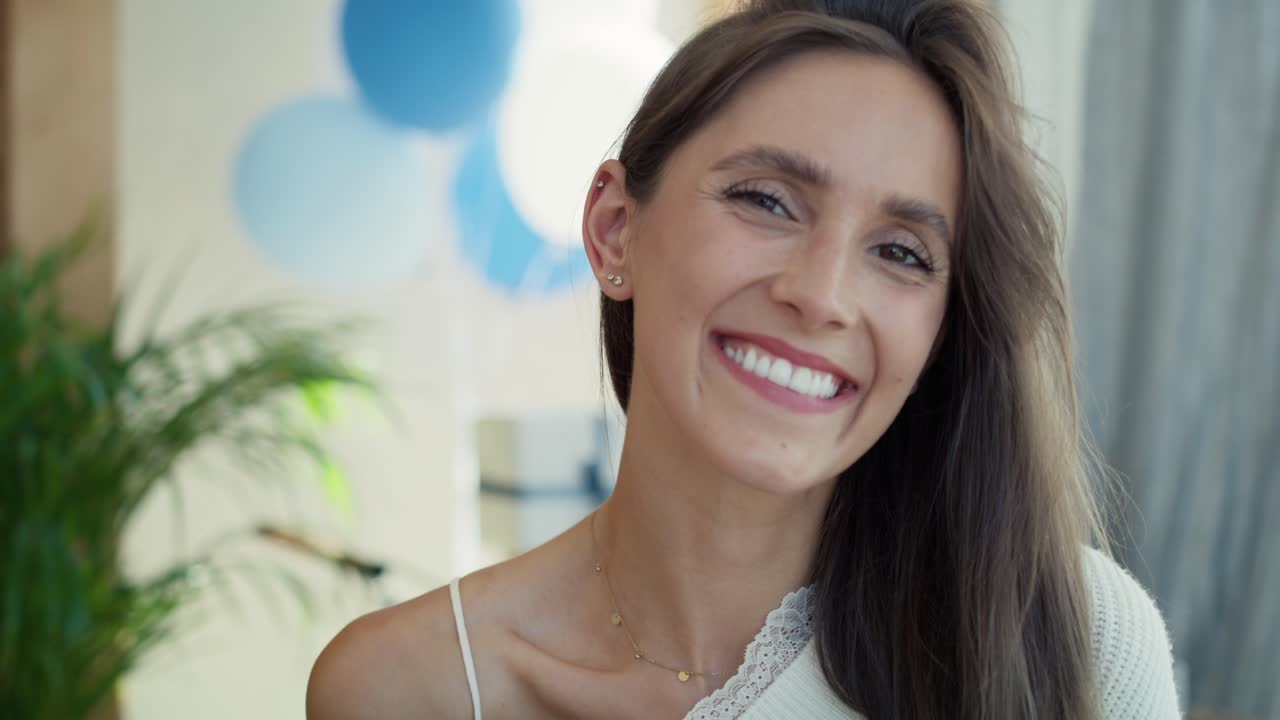 retrato de una mujer embarazada sonriente con decoraciones azules al aire libre.
