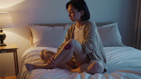 woman with a bruised knee sitting in a bedroom