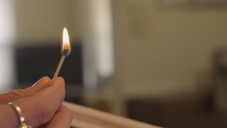 close-up-of-woman-holding-a-burning-matchstick