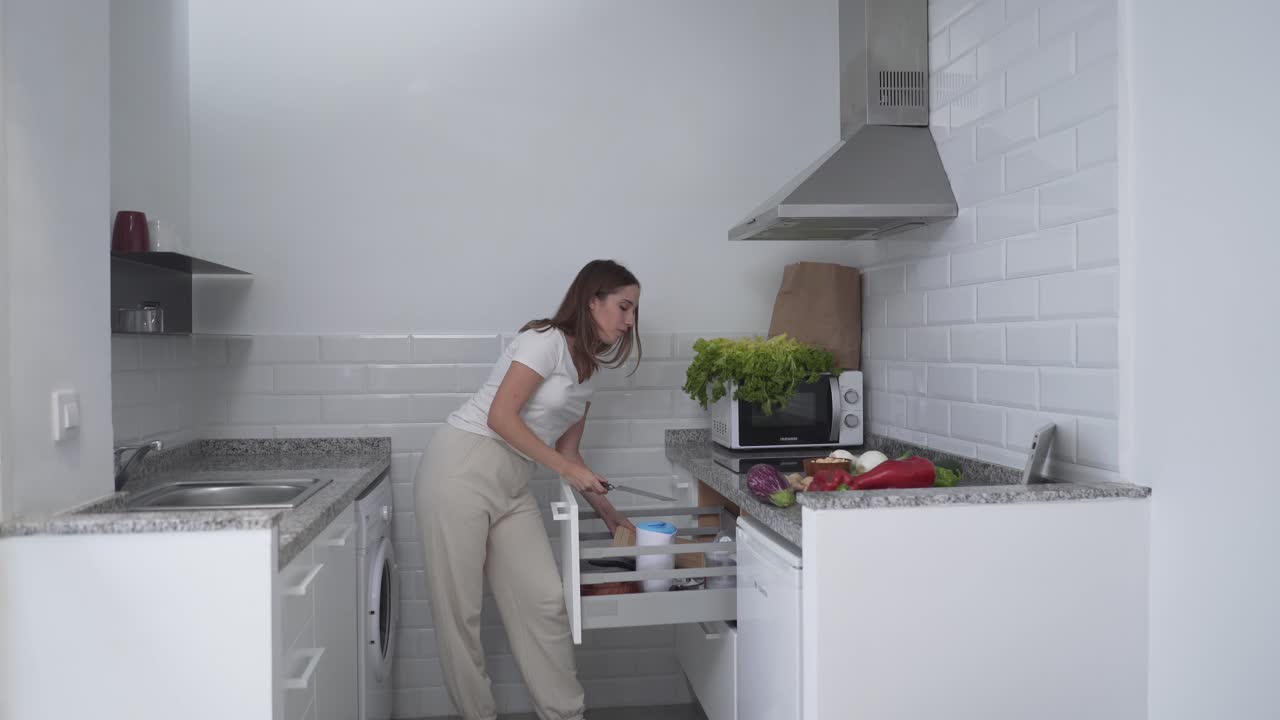 Woman preparing groceries in a small modern kitchen