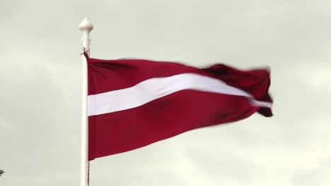 latvian flag flutters proudly in the wind against a clear sky