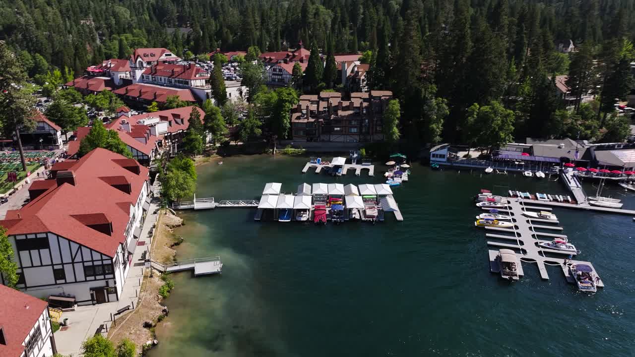 Rivelazione da dietro un pino sul villaggio di Lake Arrowhead, un porto turistico con molo per barche in una splendida giornata di sole estiva AERIAL TRUCKING PAN.