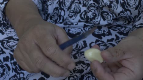 Close-Up-Of-UK-Asian-Female-Hands-Peeling-Garlic-WIth-Knife