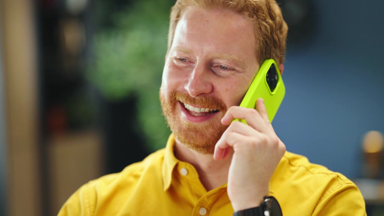 Happy Man Talking on Smartphone in Modern Office