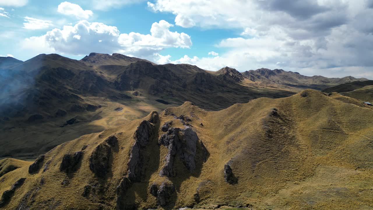 Drone footage showing a golden Andean landscape with smoke curling from a controlled burn. The scene glows in warm light and thin mountain air