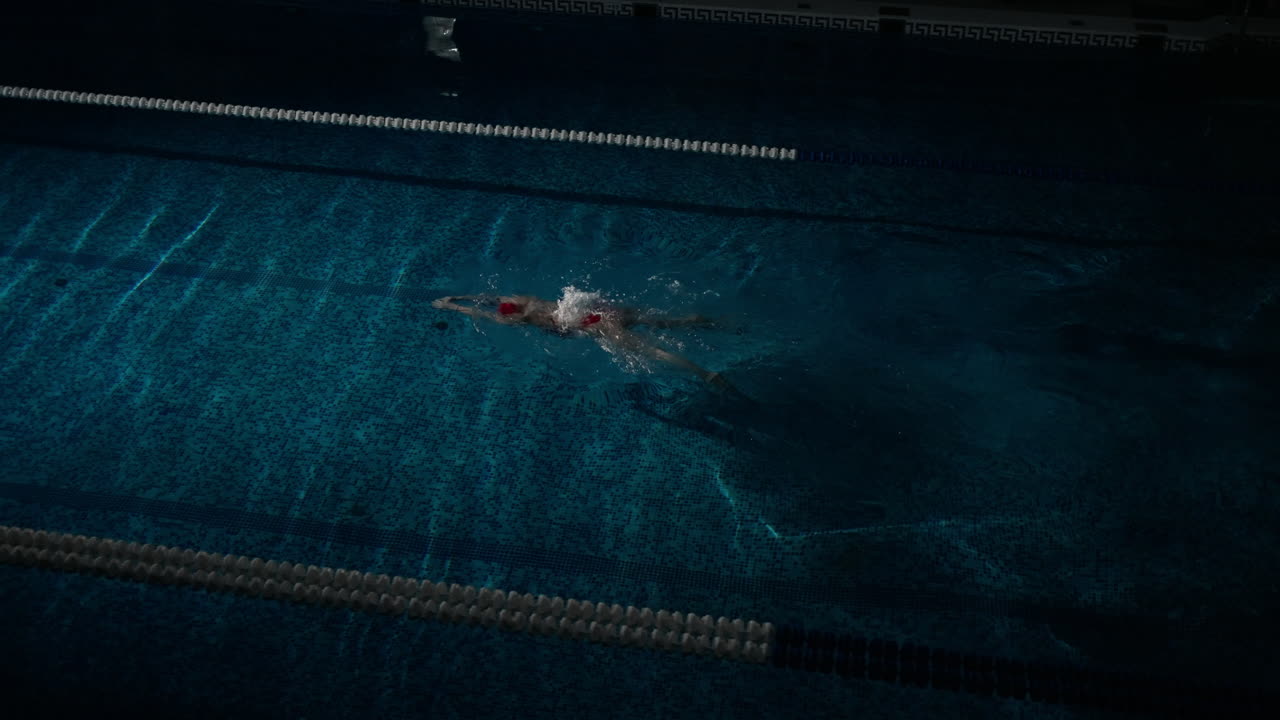 A female swimmer doing freestyle in an indoor pool