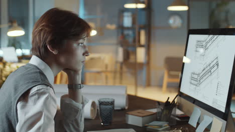 young female architect working at desk in night office