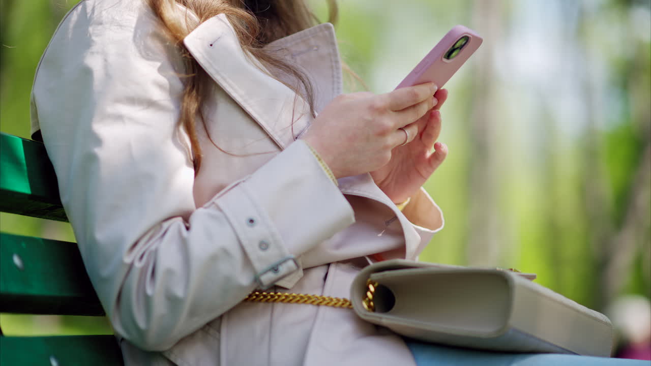 Woman scrolling through her phone on a bench in the park