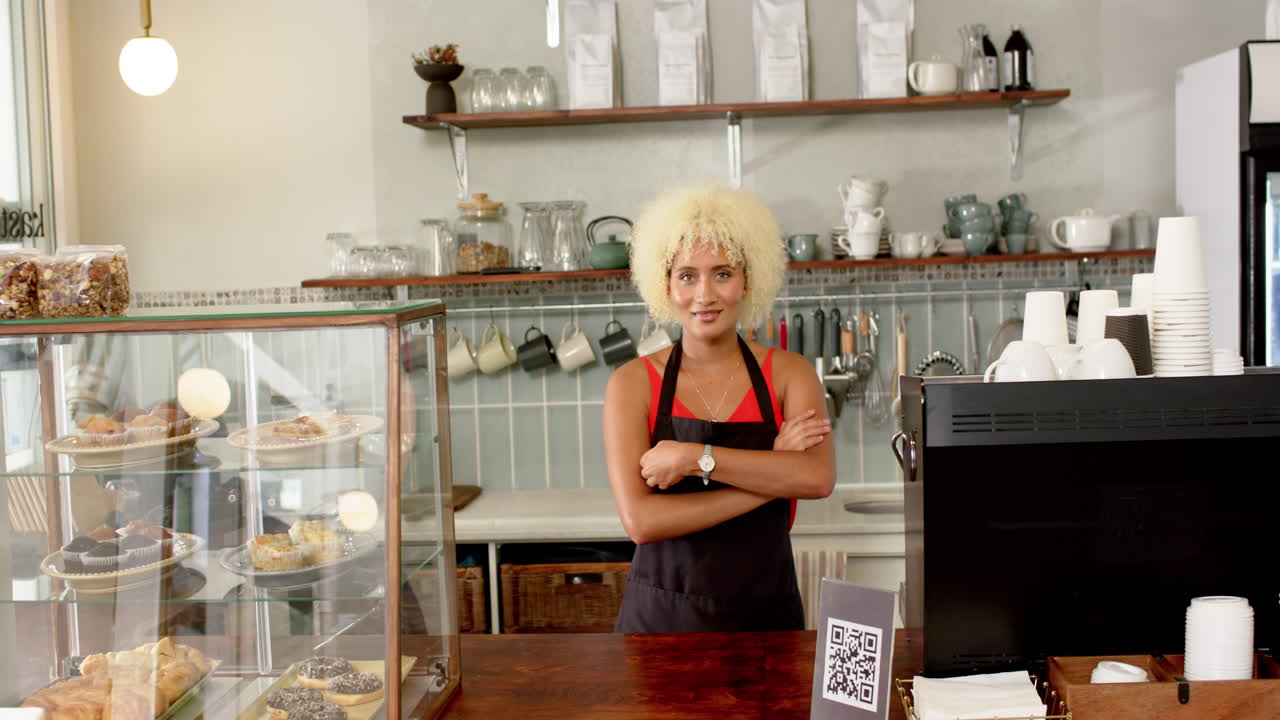 Biracial barista with curly blonde hair stands at coffee shop counter