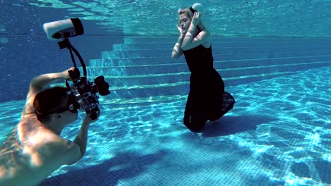 photographer professional swims and shoots underwater in the pool beautiful girl model with white hair in a suit taurus. slow motion.