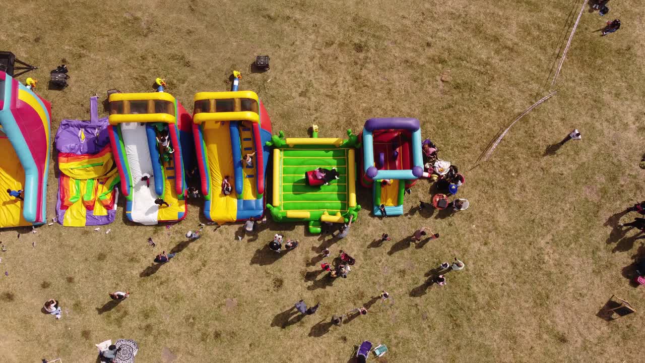 niños jugando en toboganes inflables de colores al aire libre y juegos de toros mecánicos