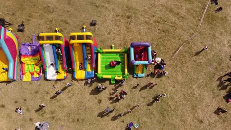 kids playing on outdoor colored inflatable slides and mechanical bull game