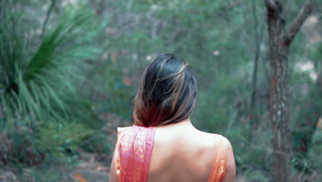 woman wearing red sari walks through the forest - medium shot