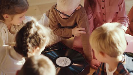 Vorschulkinder-Sitzen-Um-Einen-Speziellen-Plattenspieler-Herum,-Hören-Musik-Und-Kommunizieren-Miteinander-In-Einem-Sonnigen,-Gemütlichen-Raum-In-Einem-Club,-Um-Kinder-Auf-Die-Schule-Vorzubereiten