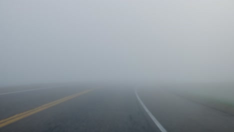 point of view of a vehicle driving down the highway in low visibility due to foggy weather conditions