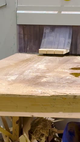 portrait video of industrial wood cutting machinery at timber merchant uses saw to split softwood plank into three smaller planks