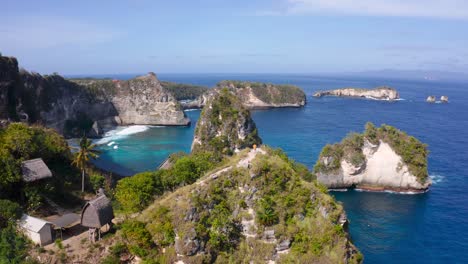distant aerial view of a person walking along the top of a cliff on the tropical island of nusa penida, indonesia