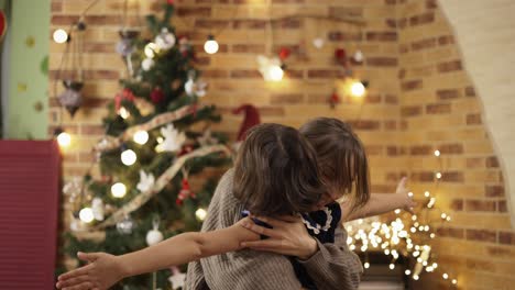 Junge-Familie-Mit-Tochter-Am-Weihnachtsbaum-Zu-Hause,-Die-Sich-Aufrichtig-Umarmt