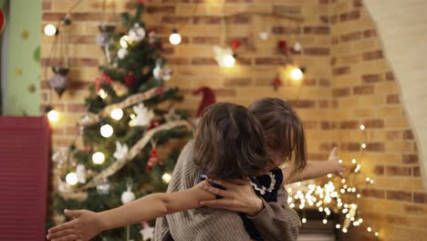 familia joven con hija en el árbol de navidad en casa abrazándose sinceramente