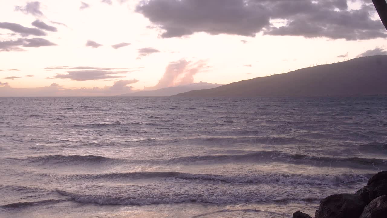 Donna in controluce contro una vista sull'oceano al tramonto