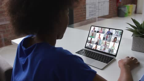 african american woman talking on video conference with office colleagues on laptop at office