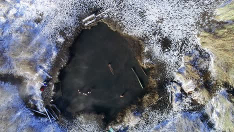 a lady laying belly up on her back in saratoga hot springs in provo utah during winter time with snow all over the ground