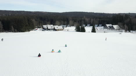 Toma-Aérea-De-Niños-En-Trineo-En-Una-Colina-De-Esquí-En-Un-Campamento-De-Esquí-De-Invierno-En-La-República-Checa