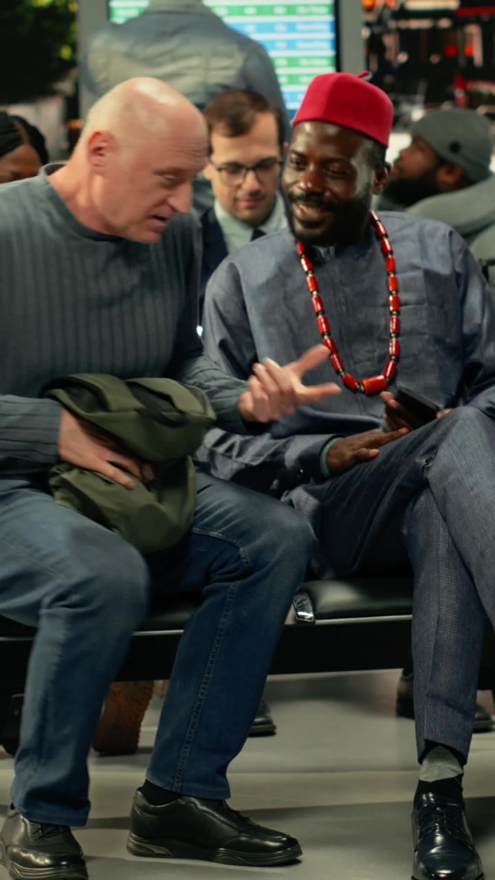 Pria mengenakan pakaian tradisional Afrika dan seorang penumpang menunggu di stasiun bus.