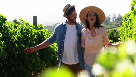 Couple-holding-hands-while-walking-at-vineyard