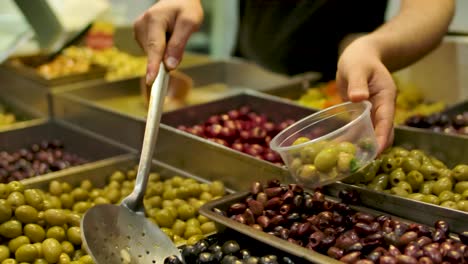 vendor scooping various salted olives into the tub on the mahane yehuda market in jerusalem, israel