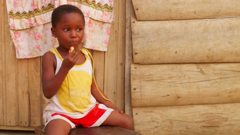 black african children eating candy in remote rural village of africa while playing alone outdoor close up of black child