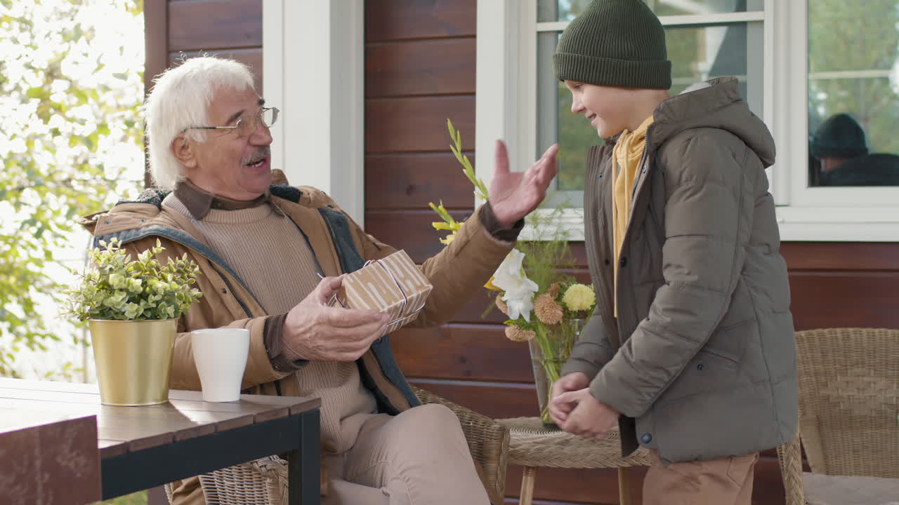 Child Bringing Present to Granddad Sitting on Terrace