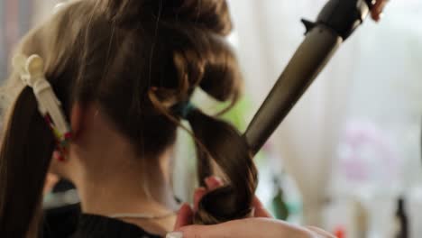 skilled stylist uses curling iron to create elegant and stunning hair curls