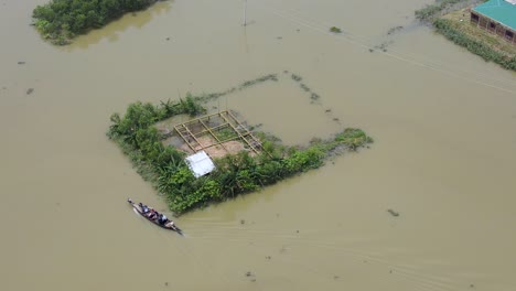 aerial view over boat transporting people in flood affected submerged village homes in bangladesh