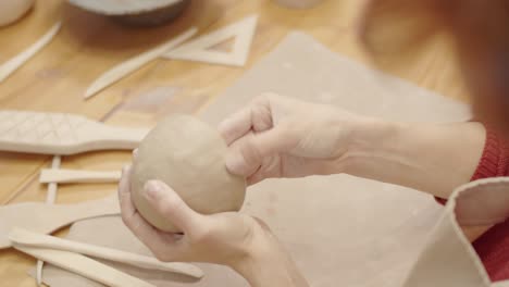 hands of anonymous female potter smoothing walls of clay bowl