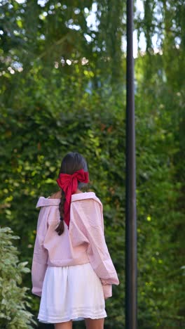 girl in pink plaid shirt and white skirt in a park