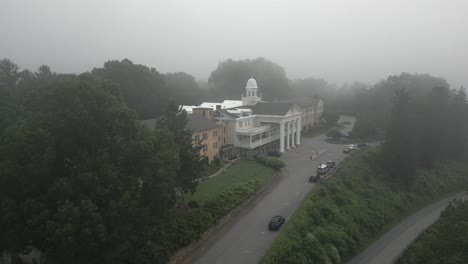Foggy-morning-aerial-orbits-stately-charming-old-hotel,-Lambuth-Inn