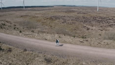 tracking shot of a young couple walking through a windfarm