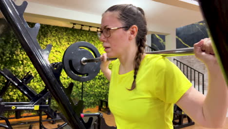 Frau-Macht-Kniebeugen-Mit-Einer-Geraden-Stange-Im-Fitnessstudio