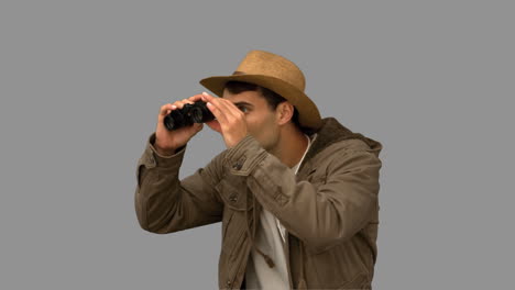 man wearing a coat using binoculars on grey screen