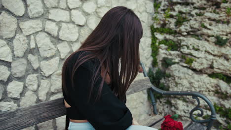 woman on the bench putting the phone in the bag and picking up flowers